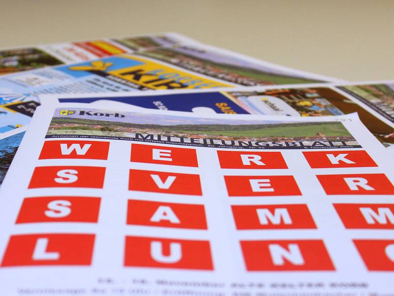 Mehrere farbige Broschüren liegen auf einem Tisch, wobei eine im Vordergrund mit dem Titel "WERK SVERSAMMLUNG" in großen roten Buchstaben hervorsticht.
