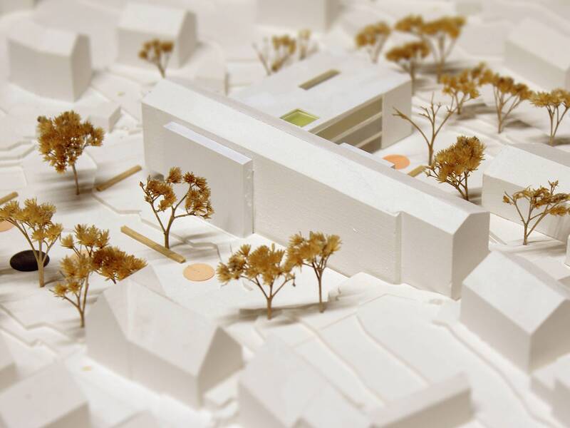 Das Bild zeigt ein architektonisches Modell einer Stadtlandschaft mit weißen Gebäuden und kleinen, stilisierten Bäumen.