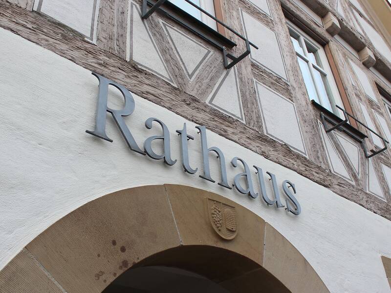 Das Bild zeigt die Fassade eines Gebäudes mit dem Schriftzug "Rathaus" und Fachwerkdetails.