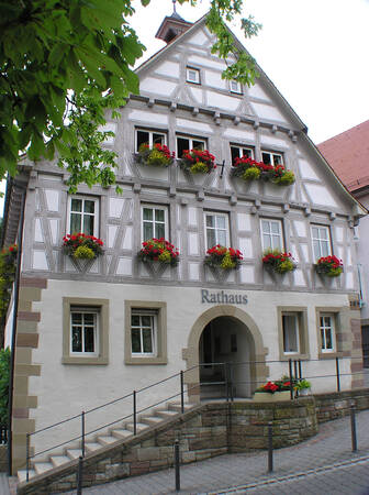 Ein traditionelles Fachwerk-Rathaus mit blumenverzierten Fenstern und einem bogigen Eingang.